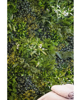 Een weelderige, gestructureerde achtergrond wordt gecreëerd door de Kunsthaag Freshness 100x100 cm UV verticale tuinmuur, dichtbegroeid met groen gebladerte. Rechtsonder zijn twee gevouwen beige handdoeken zichtbaar.