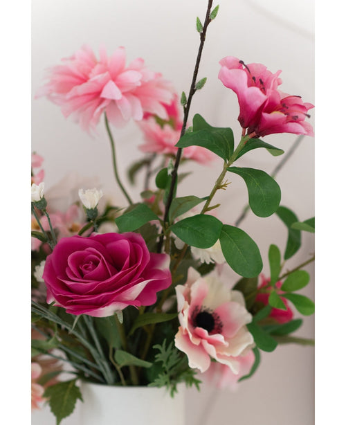 Eine Nahaufnahme der 56 cm großen künstlichen Rose „Real Touch“, einer lebensechten rosa künstlichen Rose mit grünen Blättern, präsentiert in einer weißen Vase vor einem hellen Hintergrund.